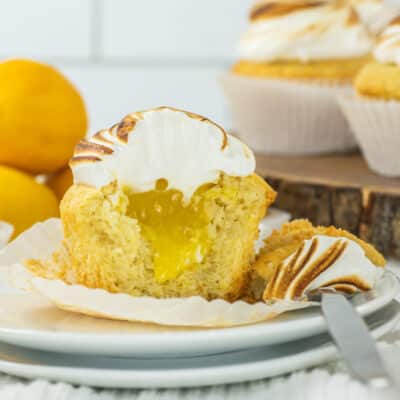 Closeup of a lemon meringue cupcake cut open to expose the lemon curd filling