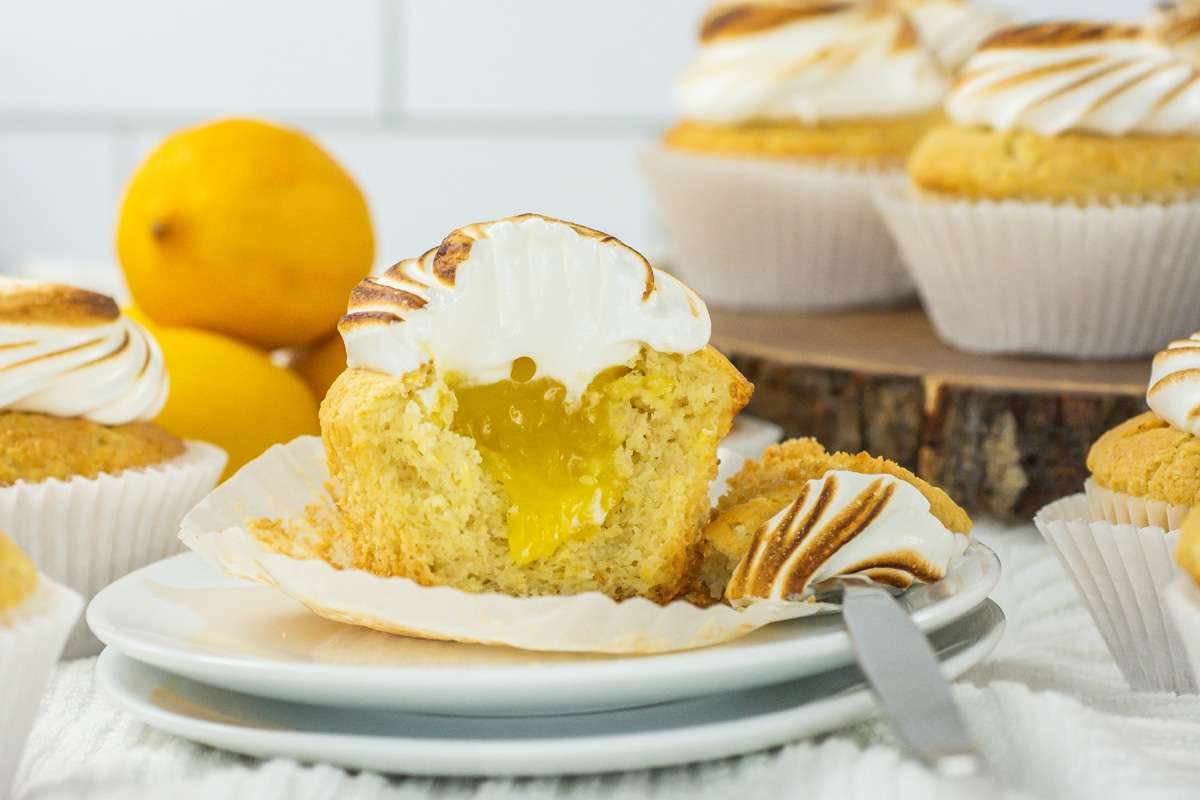 Closeup of a lemon meringue cupcake cut open to expose the lemon curd filling