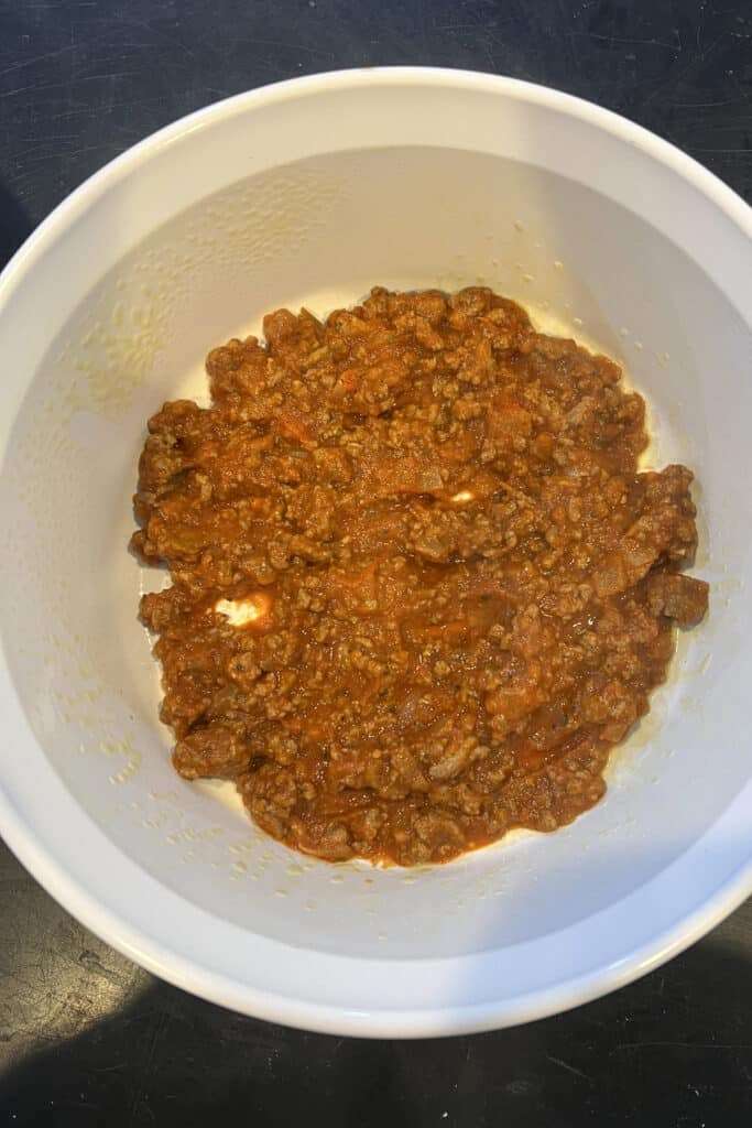 add a layer of the meat sauce to the bottom of the casserole dish