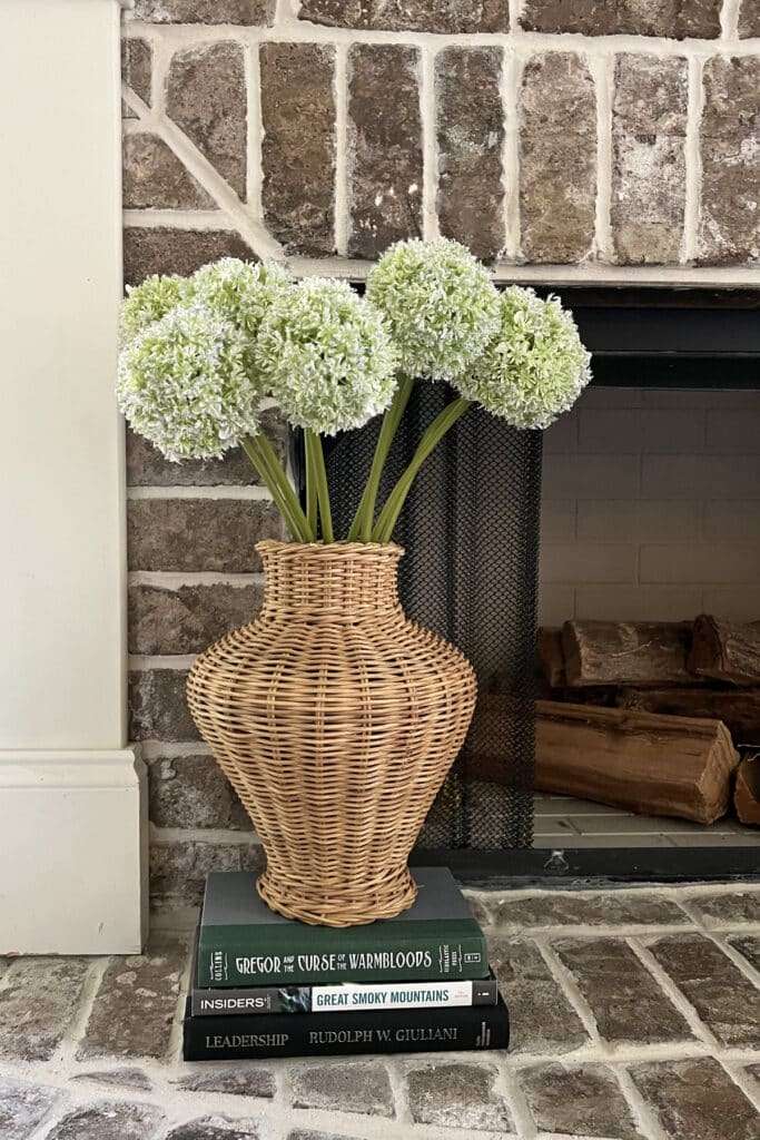 Wicker vase with long stem artificial flowers on a base of stacked books