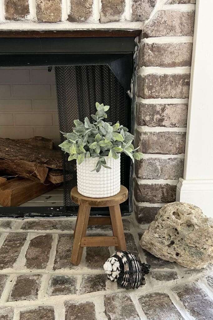 Textured white flower pot with a mini plant sitting on a small wooden stool
