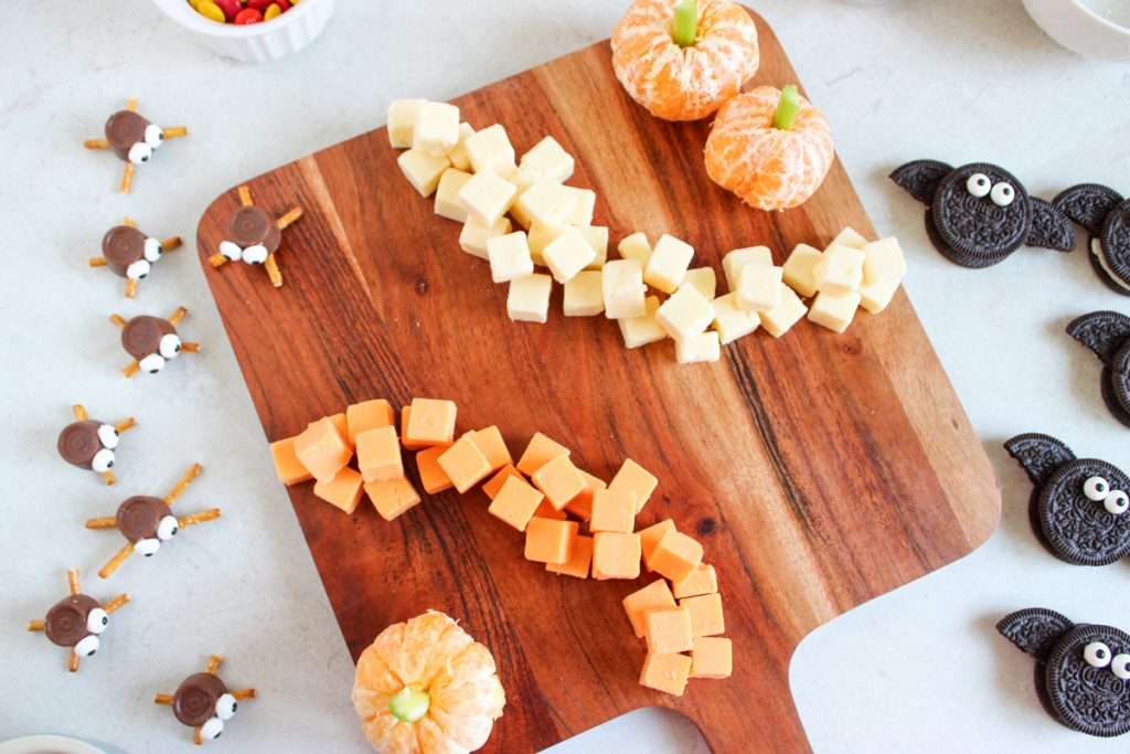 Arrange cheese cubes in curved lines on opposite sides of the board