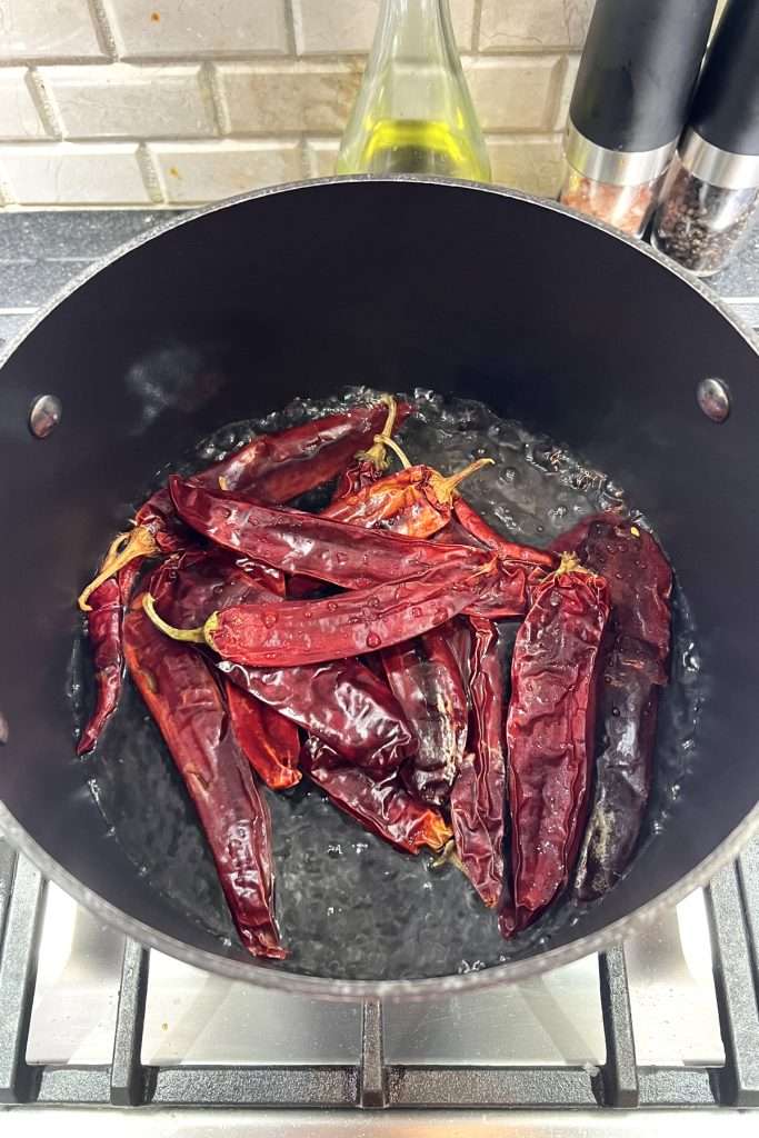 Boil water, then turn off heat. Place peppers in the water and submerge.