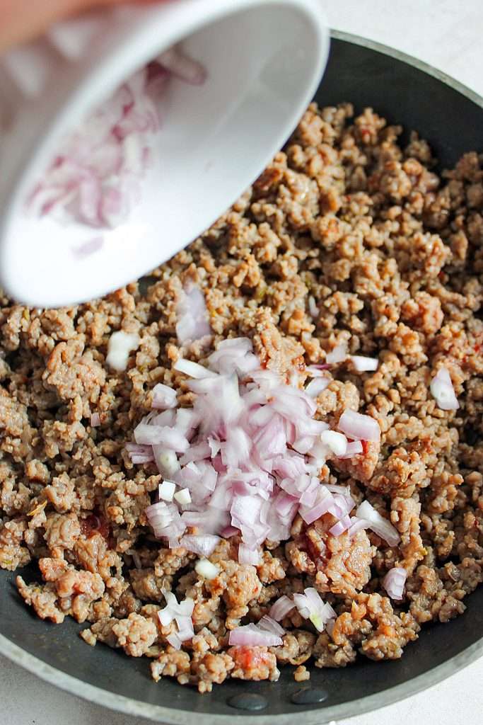 Cook sausage, then add onion and garlic. Saute until veggies soften.