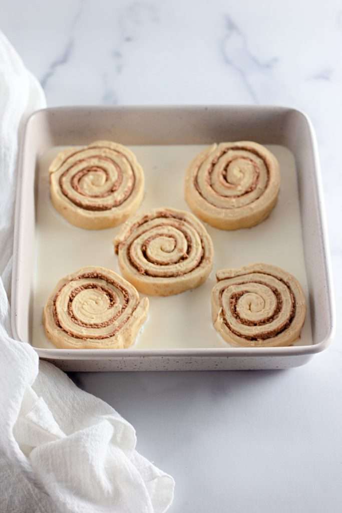 Pour heavy cream in a banking pan and place cinnamon rolls on top