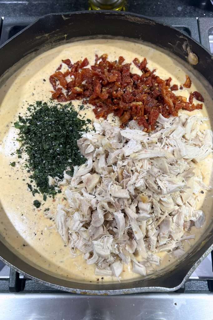 Add basil, sun-dried tomatoes, and cooked chicken.