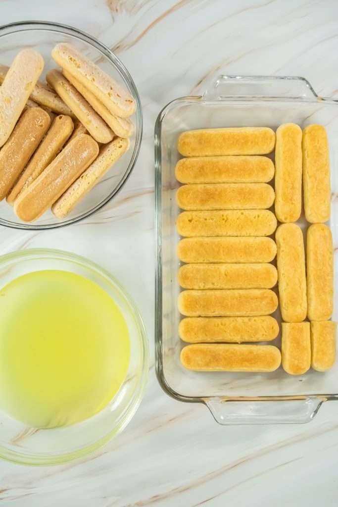 Begin by unwrapping your ladyfinger cookies and have them ready alongside your previously cooled limoncello syrup.