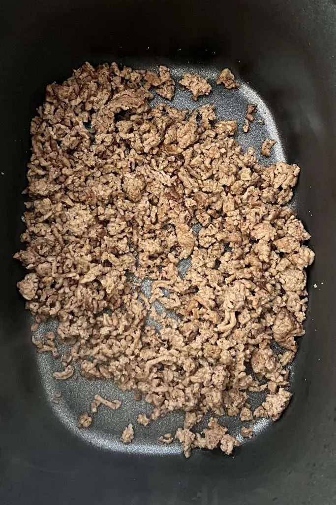Add cooked and seasoned ground beef to crockpot.