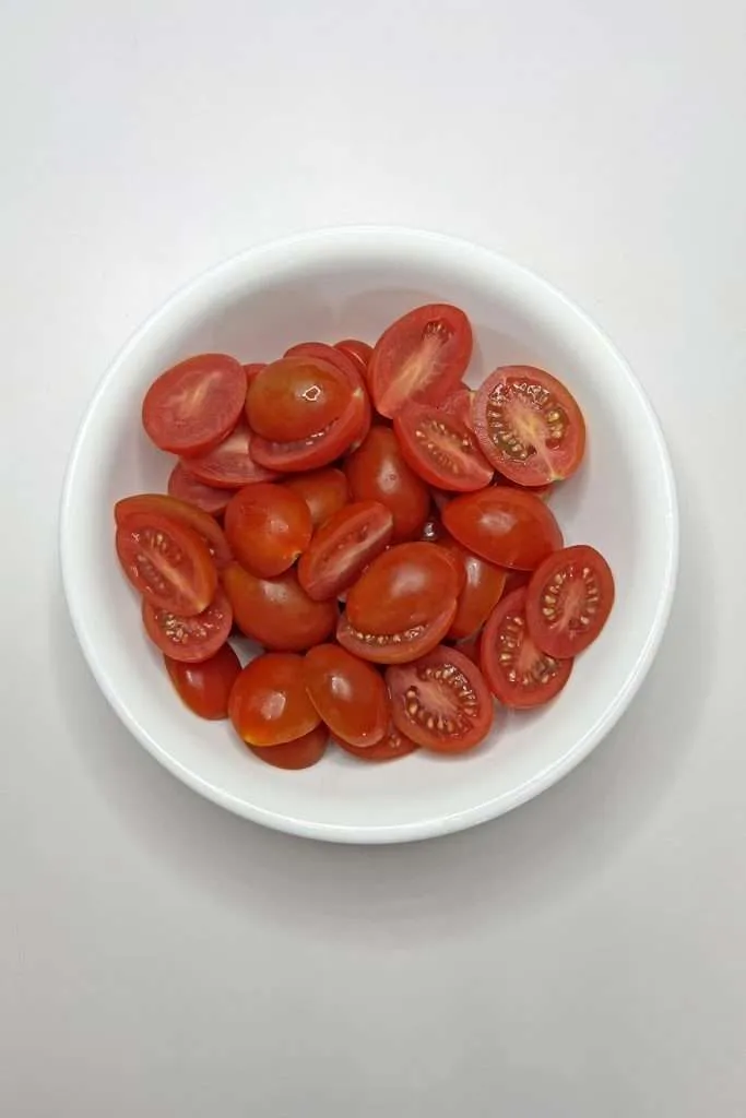 Slice grape tomatoes in half