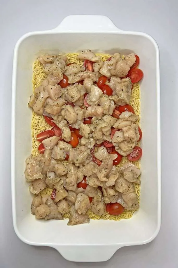 Layer orzo, seasoned chicken, and tomatoes in a casserole dish