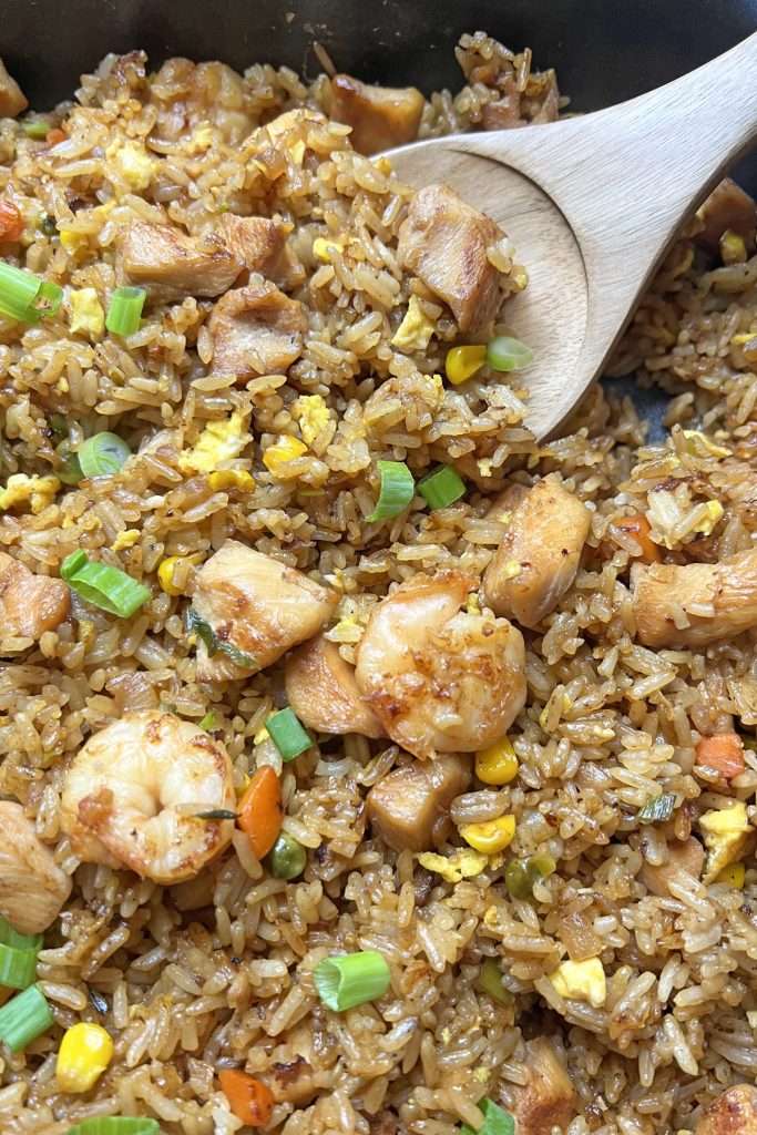 shrimp and chicken fried rice in skillet with spoon