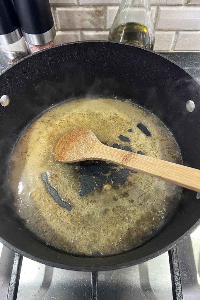 Deglazing a skillet with white wine and a wooden spoon.