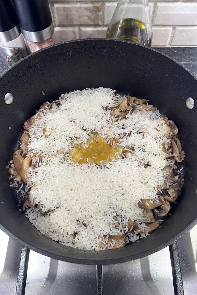 Rice and bouillon added to a skillet.
