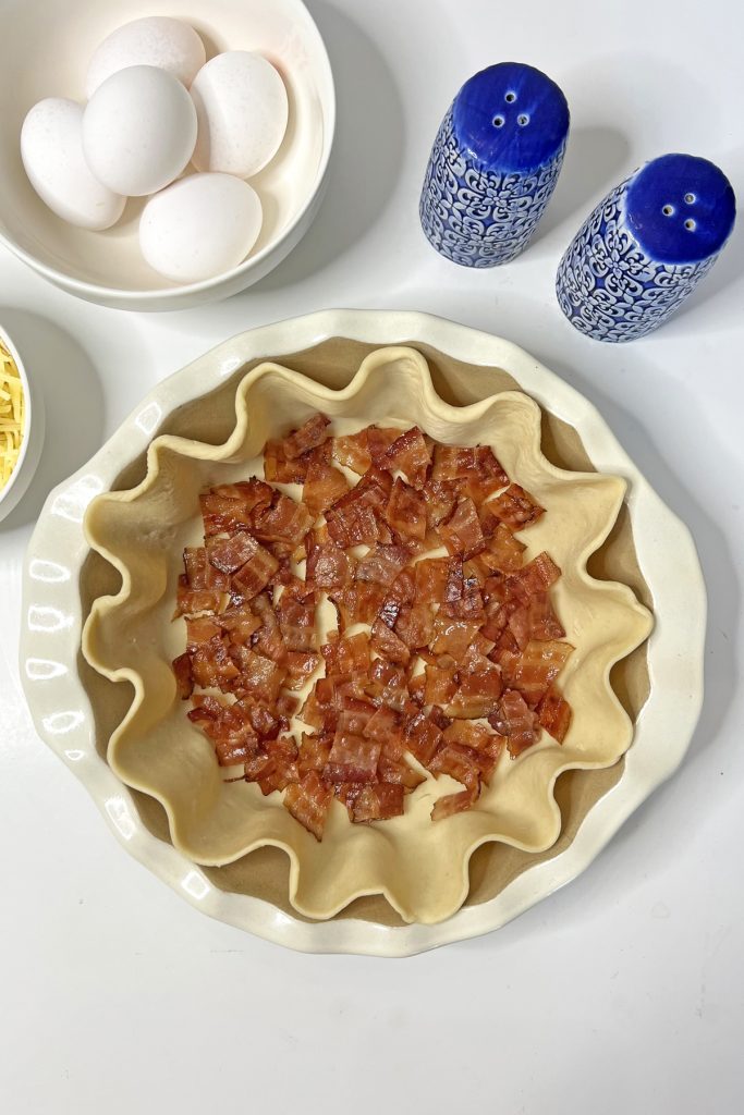 Add an even layer of bacon to the crust.