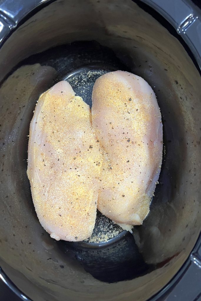 Place chicken breasts in crockpot and season.