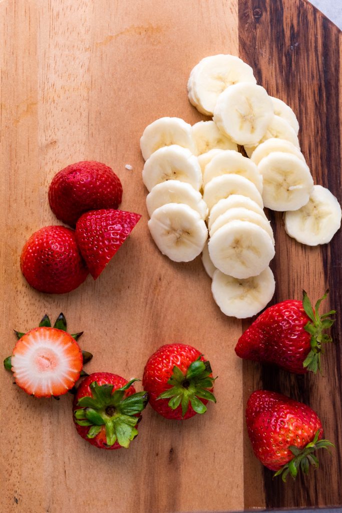 Slice the banana and cut the top leaves off of the strawberries.