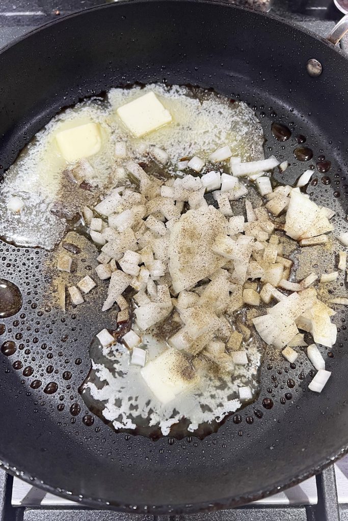 Diced onion cooking in a skillet with butter and olive oil.