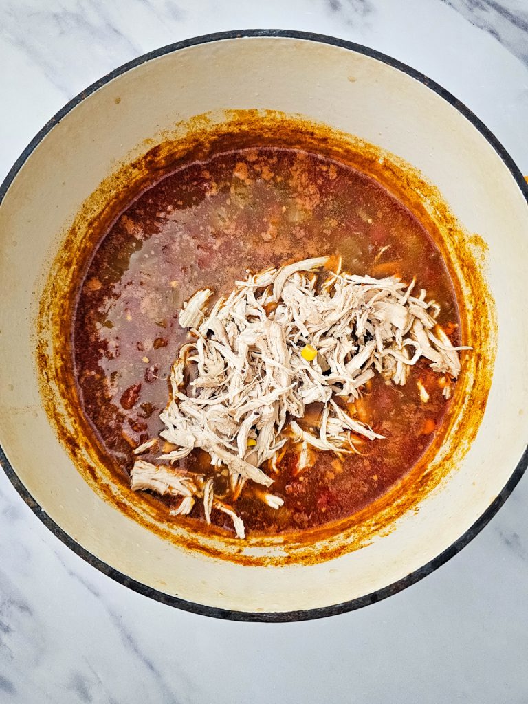 Soup in a Dutch oven with shredded chicken.