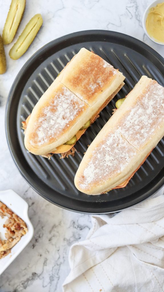 Cuban sandwiches grilling on a press.