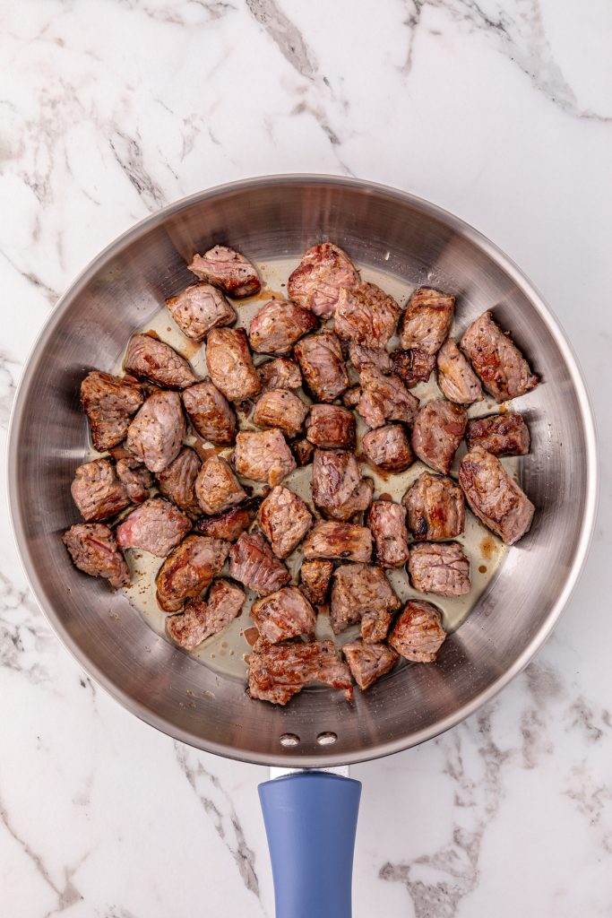 Stew meat being seared in a pan