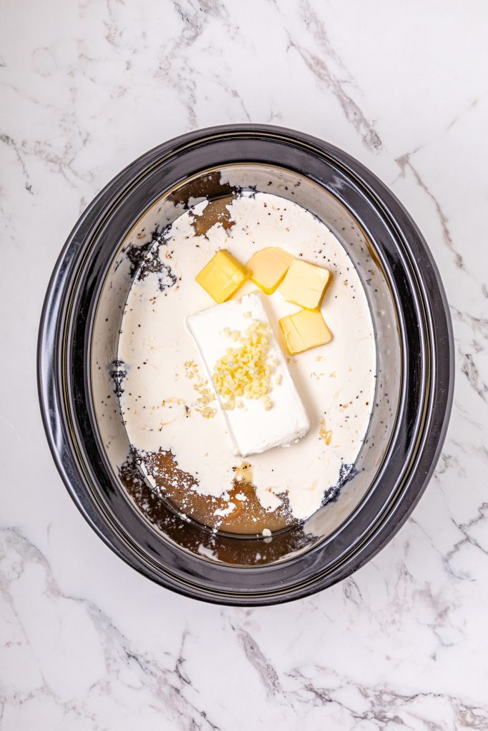 Heavy cream, cream cheese, butter, and garlic over chicken in a crockpot.