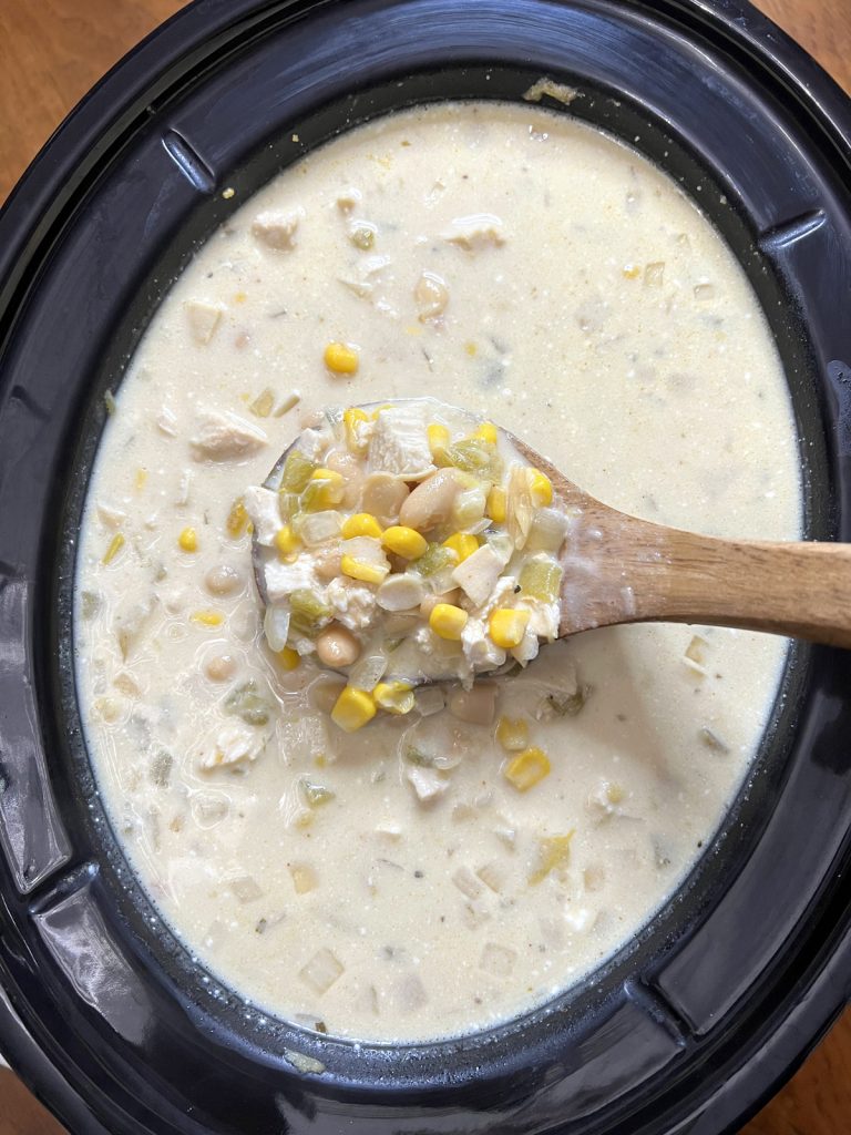 White chicken chili in a crockpot with a wooden ladle.