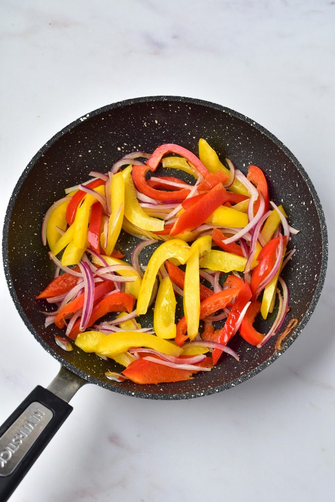 Bell peppers cooking in a skillet.