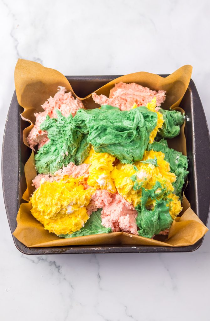 Prepared candy melts and whipped topping in different colors in a baking dish.