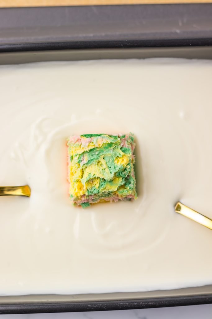 Frozen candy square being dipped in white chocolate.