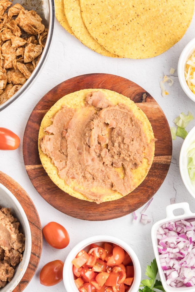 A thin layer of refried beans spread on a tostada shell.