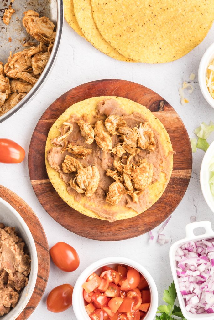 Chicken chunks and refried beans on a tostada shell.