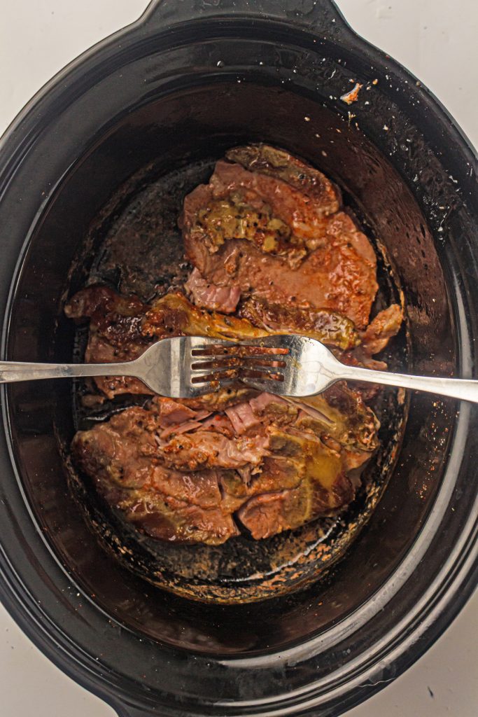 Shredding pork in a crockpot with 2 forks.