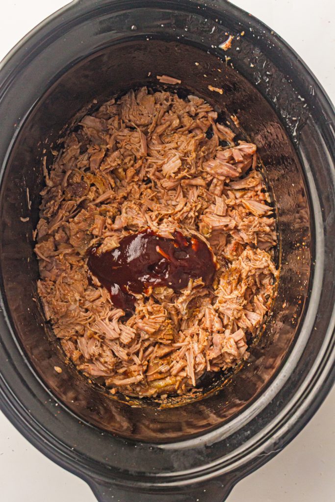 Shredded pork in a crockpot with barbecue sauce on top.