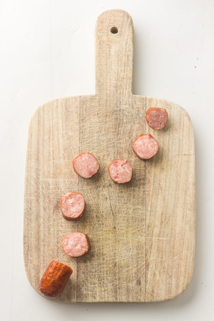 Slices of sausage on a wooden cutting board.