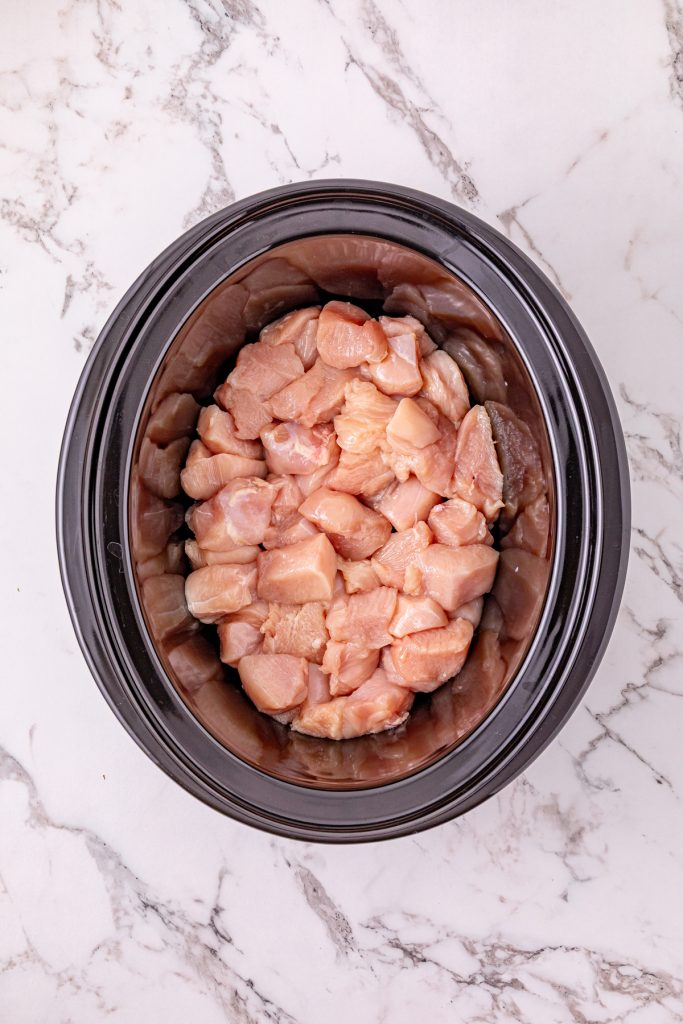 Chopped chicken pieces in a crockpot.