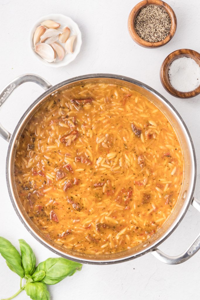 Orzo simmering in a skillet.